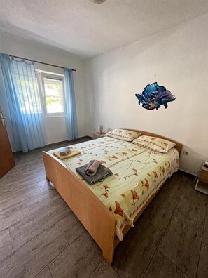 Ein Schlafzimmer mit einem hölzernen Bett, einem Fenster mit Vorhängen und einer Wanddekoration.
