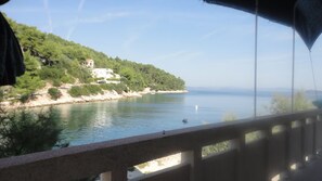 Une vue sur une étendue d’eau, avec un bâtiment situé sur une colline, une balustrade au premier plan et un ciel dégagé.