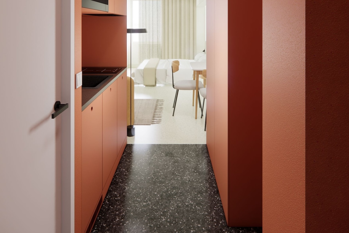 Un pasillo con cocina, comedor y una habitación con cama y silla.