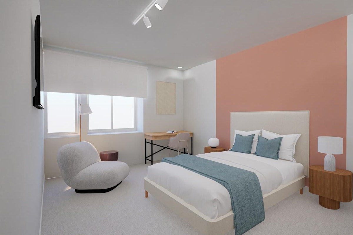Un dormitorio moderno con cama, mesitas de noche, un escritorio y una silla.