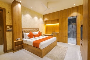 Ein modernes Schlafzimmer mit einem großen Bett, Holzvertäfelung, einem Deckenventilator und einem Badezimmer mit Glastür.