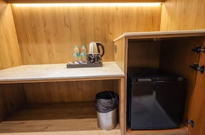 A compact kitchenette with a countertop, a coffee maker, water bottles, and a trash bin. - OnlyStay DD Dham Prem Mandir, Vrindavan (Vrindavan)