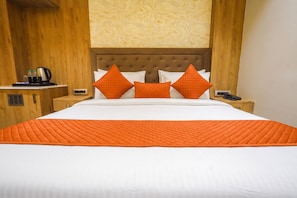 A hotel room with a large bed, a wooden headboard, and a nightstand with a phone and a kettle. - OnlyStay DD Dham Prem Mandir, Vrindavan (Vrindavan)