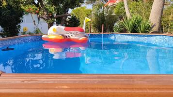 Ein Schwimmbecken mit einem schwimmenden Spielzeug und einer Holzterrasse.