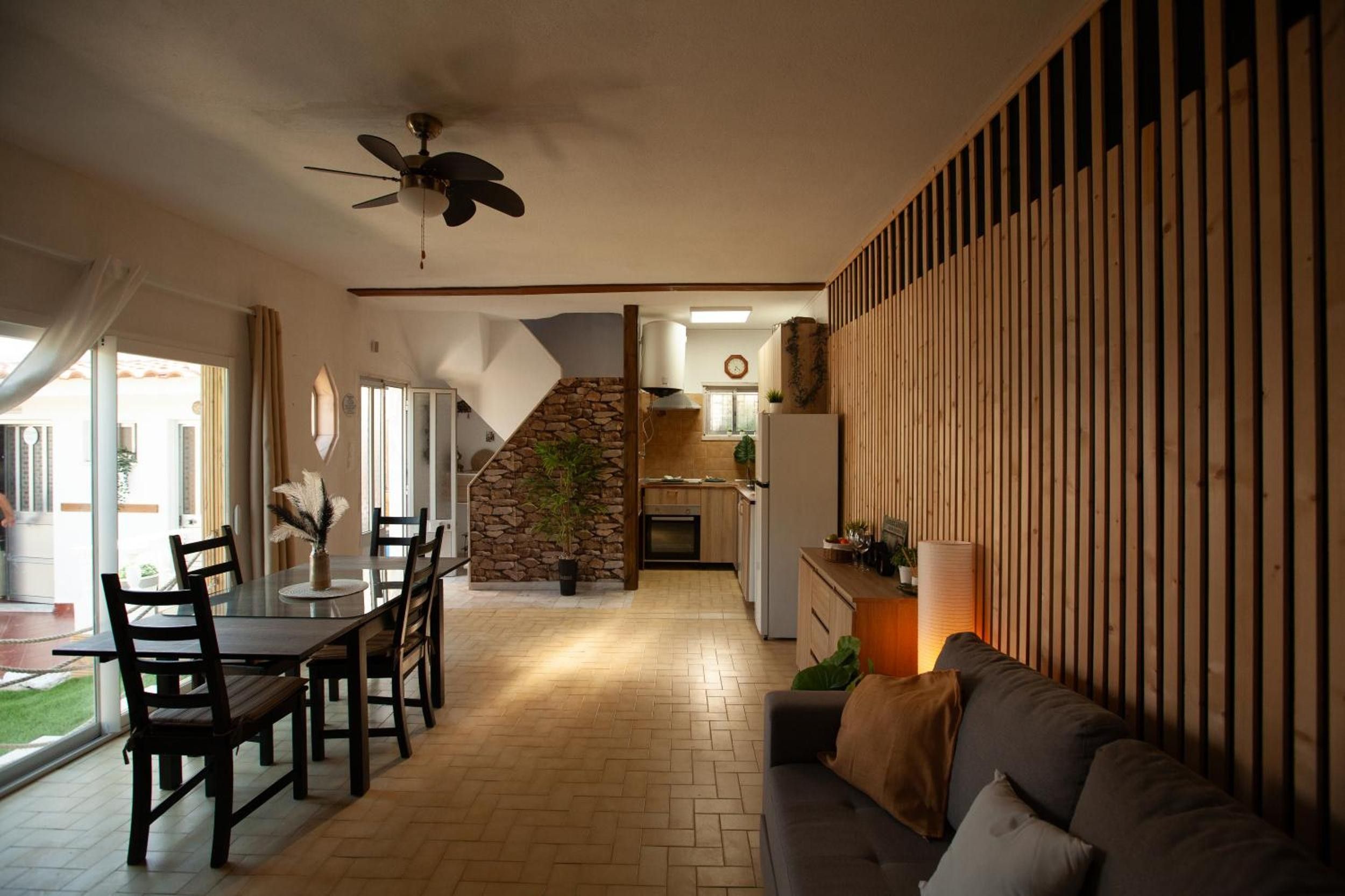 A spacious living area with a dining table, chairs, a sofa, and a kitchen in the background.