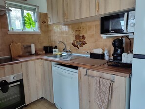 A kitchen with wooden cabinets, a sink, a microwave, a coffee maker, and a toaster. - Aroeira Garden Villa (Aroeira)