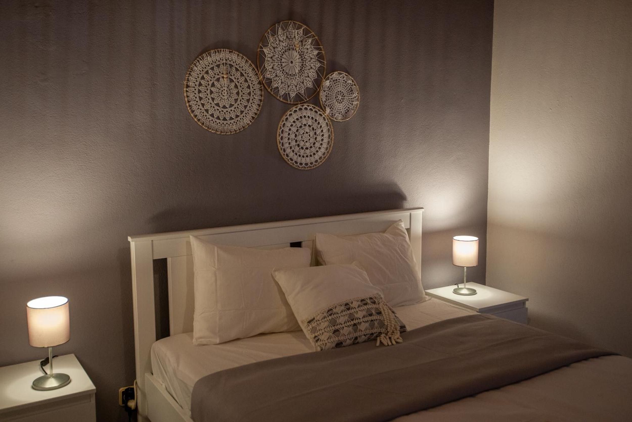 A bedroom with a bed, two bedside lamps, and wall decor.