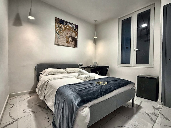 Un dormitorio con cama, mesita de noche y ventana.