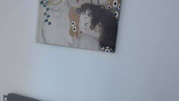 Une chambre à coucher avec un lit, une table de chevet, un tableau accroché au mur et un sol carrelé.
