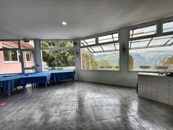 A spacious room with large windows offering a mountain view, a long table with blue tablecloths, and a brick counter. - Bed and Breakfast 'Ignis - Chambre 4' with Mountain View, Wi-Fi and Air Conditioning (Berre-les-Alpes)