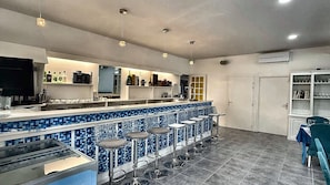 A bar area with a tiled backsplash, bar stools, and overhead lighting. - Bed and Breakfast 'Natura - Chambre 1' with Mountain View, Wi-Fi and Air Conditioning (Berre-les-Alpes)