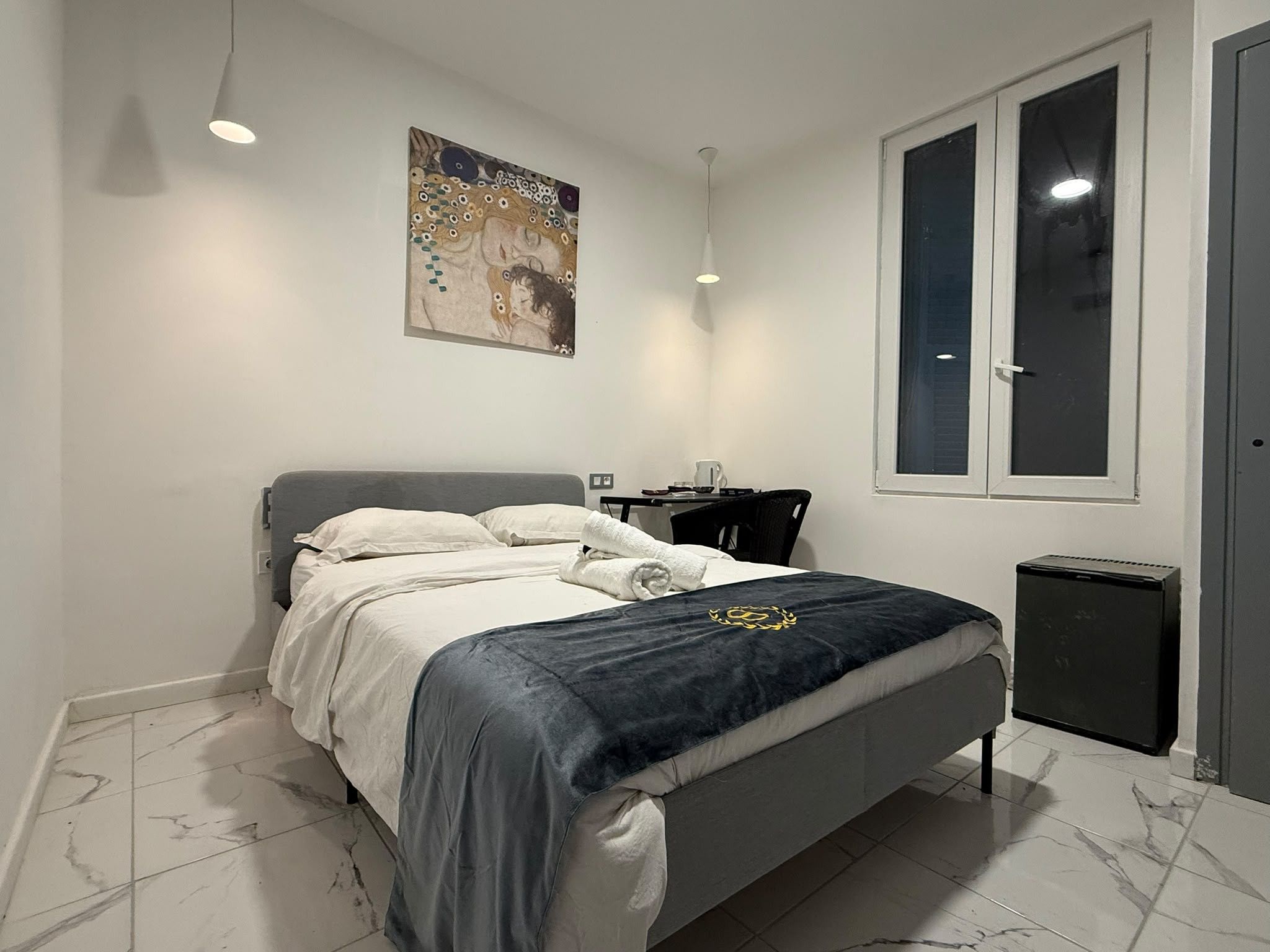 A bedroom with a bed, a nightstand, a window, and a door.