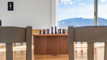 A chessboard on a wooden table with a mountain view through a window.