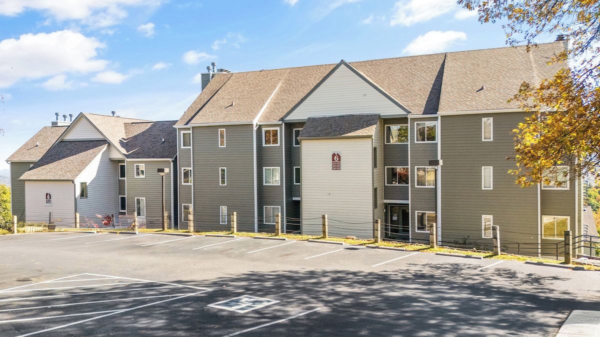A multi-story residential building with a parking lot in front.