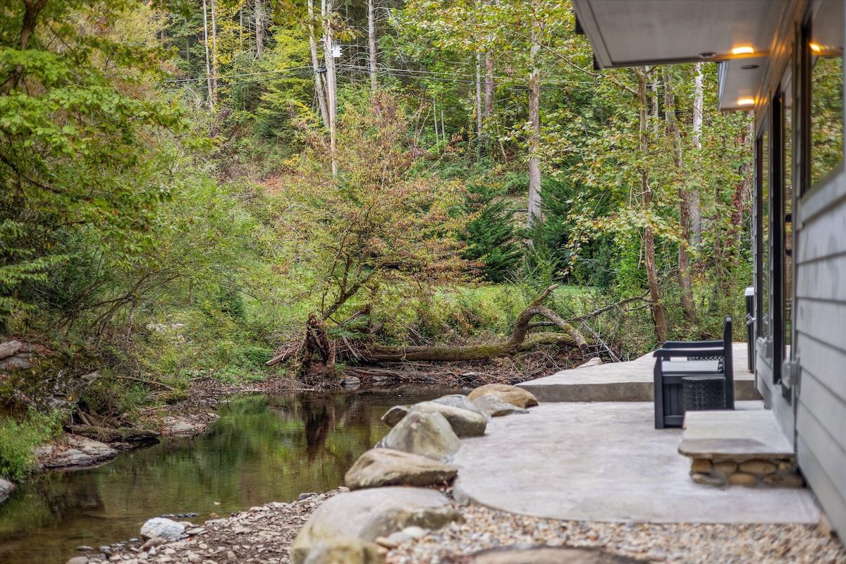 A stone pathway leading to a building with a view of a forested area and a body of water.
