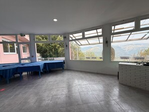 Una habitación amplia con ventanas grandes, piso de baldosas y una mesa lista para comer.