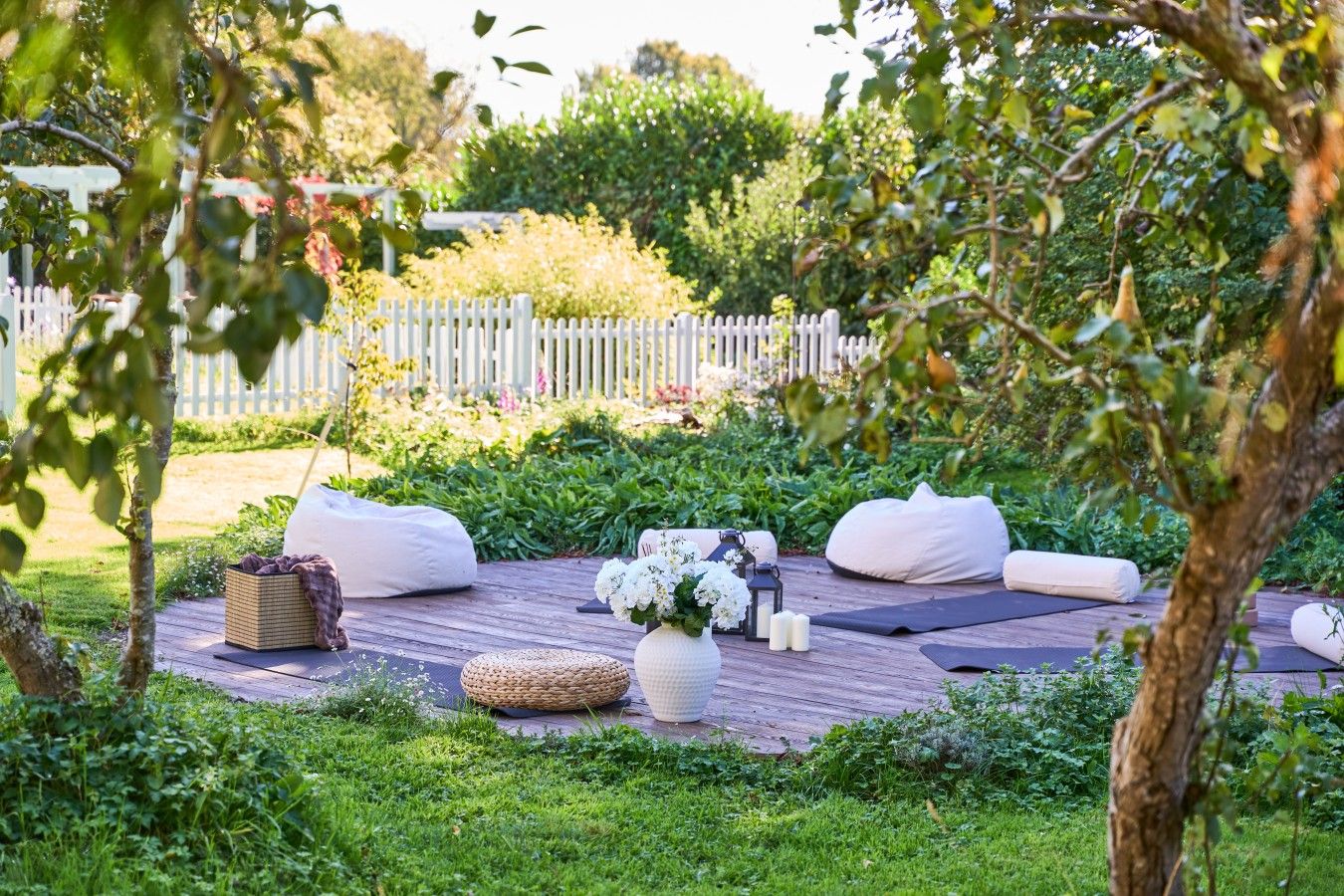 An outdoor seating area with bean bags, a woven basket, and a vase of flowers.