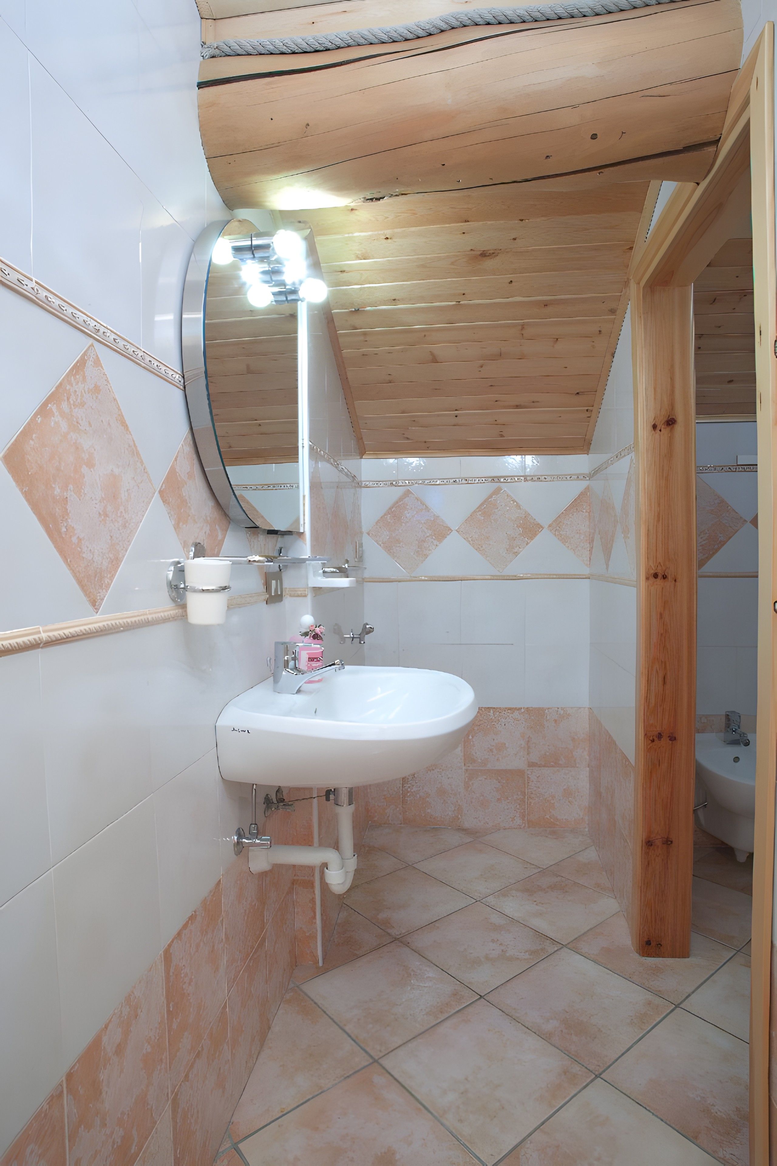 A bathroom with a white sink, a mirror, and a wooden ceiling.