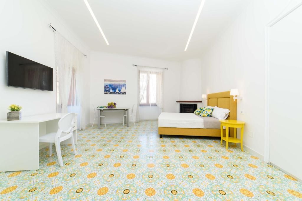 Une petite pièce lumineuse, avec un lit, un bureau et un téléviseur.