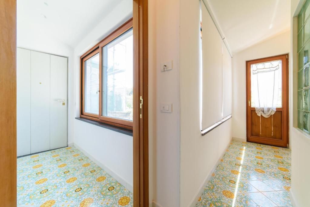 Un pasillo con suelo estampado, una puerta de madera con cortina y una ventana con marco de madera.