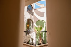 Ein Innenraum mit Balkon, einer Zimmerpflanze und einem Fenster mit Vorhang.