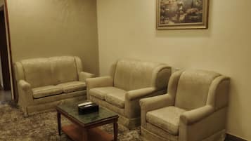 A room with two beige armchairs, a small wooden coffee table, and a framed painting on the wall.