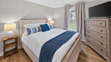 A bedroom with a bed, bedside tables, a dresser, and a television.
