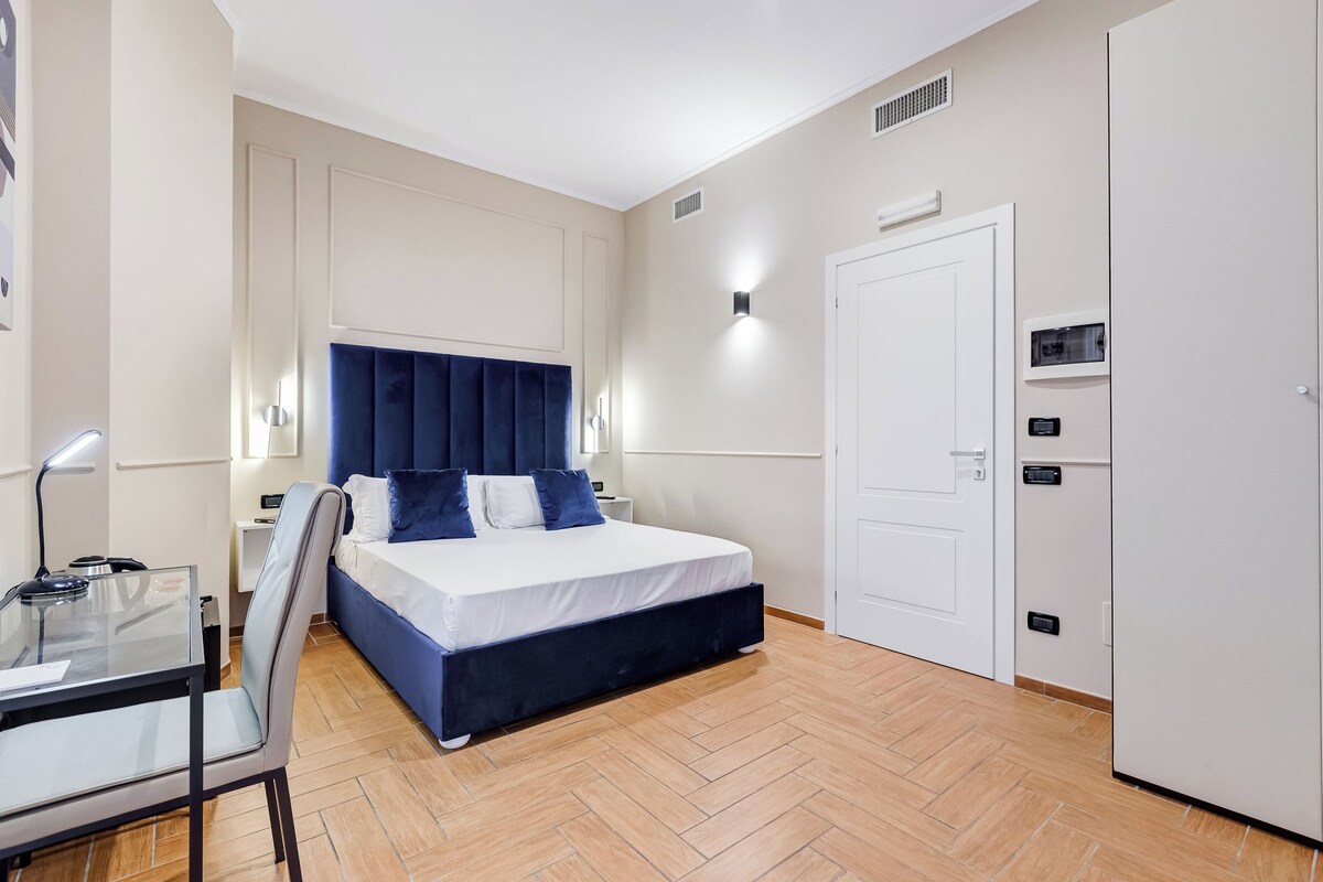 A modern bedroom with a bed, bedside table, chair, and wardrobe.