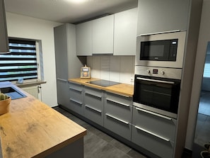 Eine moderne Küche mit grauen Schränken, einer Holz Arbeitsplatte, einer eingebauten Mikrowelle und einem Ofen.