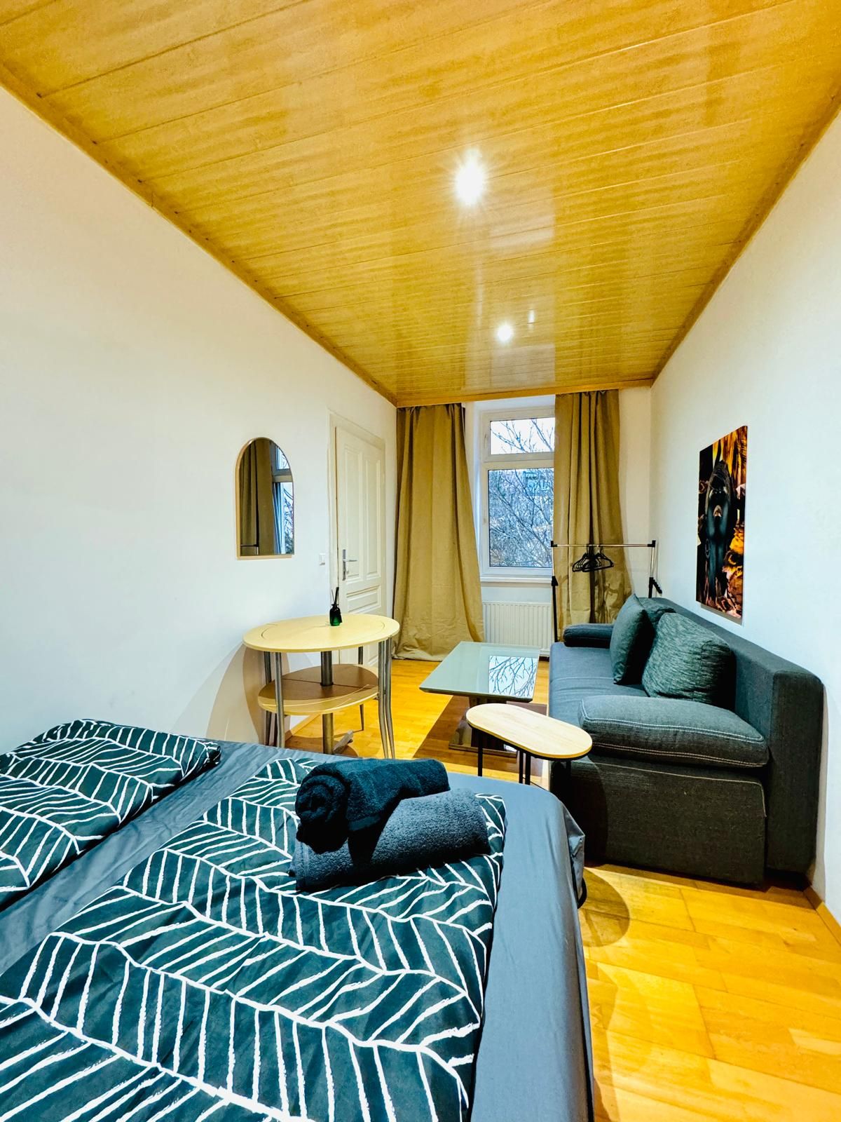 Een kamer met twee bedden, een slaapbank, een tafeltje en een raam met gordijnen.