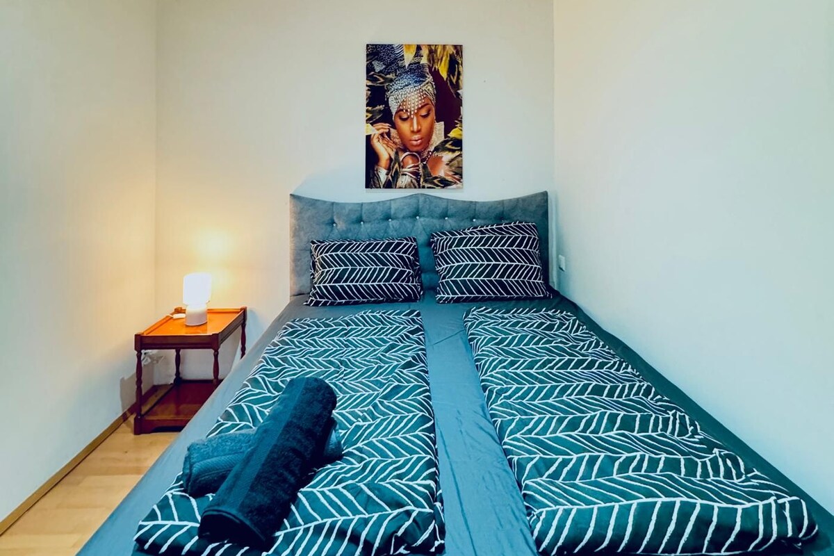 Un dormitorio con una cama, una mesita de noche y una obra de arte colgada en la pared.