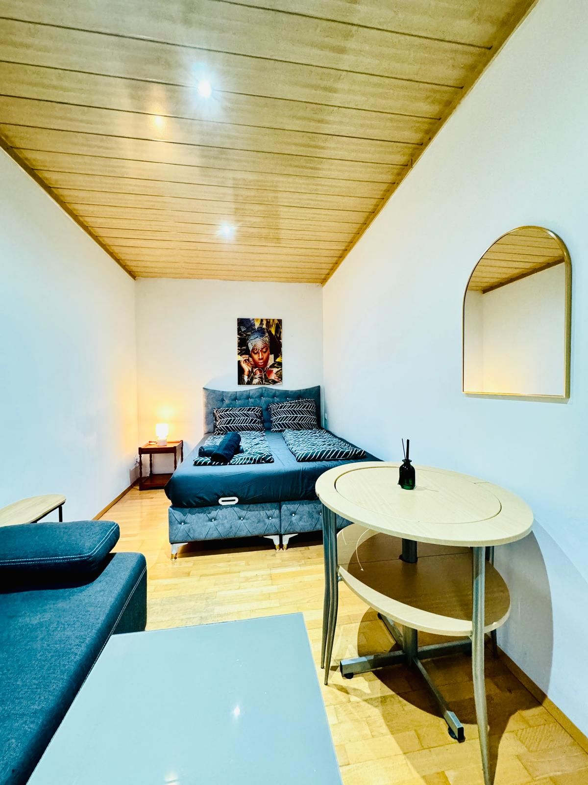 A compact room with a bed, a small table, and a mirror.