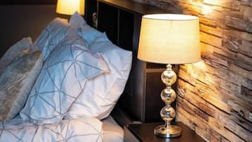 Une chambre à coucher avec un lit, une table de chevet, une lampe et un mur à texture.