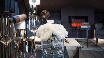 Une table à manger avec une assiette blanche, des verres à vin et un vase contenant une fleur blanche.