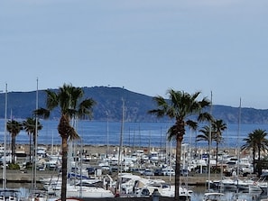 A marina with numerous boats docked, palm trees, and a mountainous backdrop. - Charming Air-Conditioned Studio with Balcony, Steps from the Beach (Cavalaire-sur-Mer)