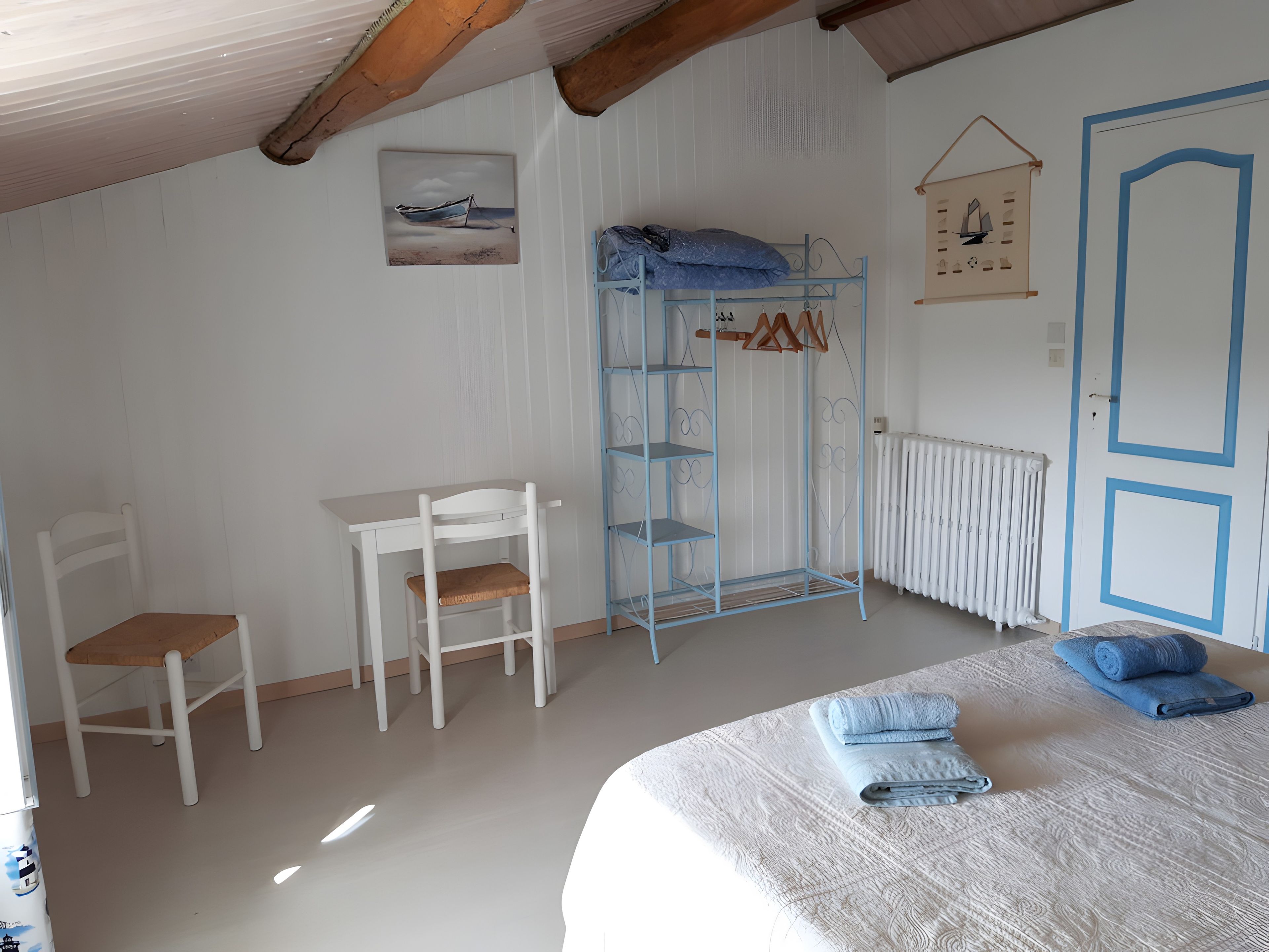 Une chambre à coucher comprenant un lit, une chaise, une petite table, un radiateur et une armoire.