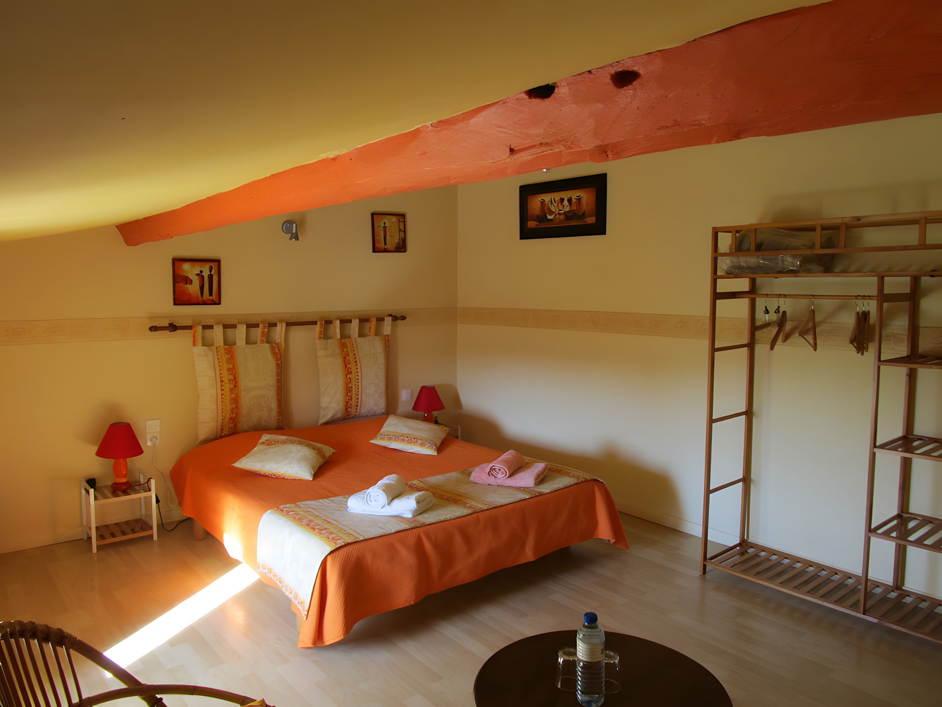 Ein Hotelzimmer mit einem Bett, einem Sessel, einem Tisch, einem Etagenbett und einem Wandregal.