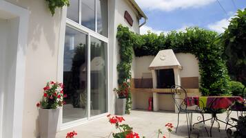 Ein modernes Haus mit Terrasse, Grill und Blumentöpfen.