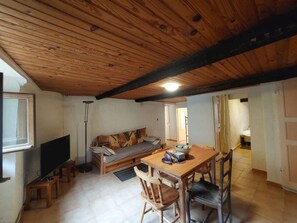 A cozy living room with a wooden ceiling, a sofa, a TV, and a dining table with chairs. - New Listing (Breil-sur-Roya)