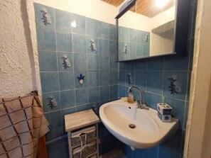 A bathroom with a white sink, blue tiles with floral patterns, a mirror above the sink, and a towel rack.