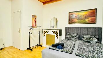 A bedroom with a bed, a dresser, a mirror, and a painting on the wall.