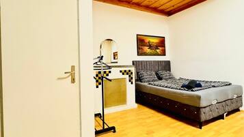 A bedroom with a bed, a wardrobe, a mirror, and a painting on the wall.