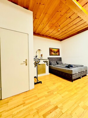 A bedroom with a bed, a wardrobe, a mirror, and a painting on the wall. - Vienna Basecamp Private Room (Wien)