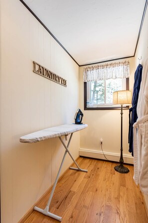 A laundry room with a hanging rack, an ironing board, and a lamp. - Aspen Song Mountain Retreat (Jefferson County)
