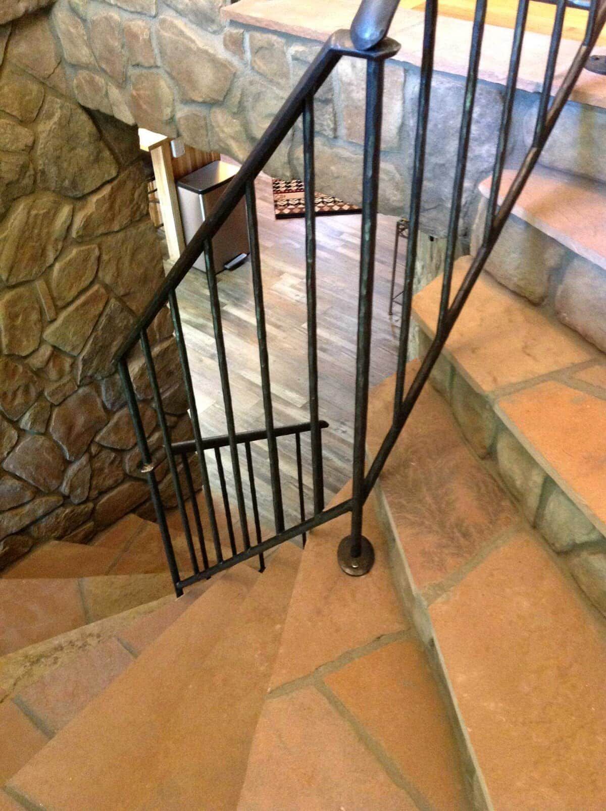 A staircase with a stone wall on one side and a metal railing.