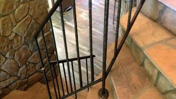 A staircase with a stone wall on one side and a metal railing.