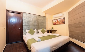 A hotel room with a bed, a door, a wall-mounted air conditioner, and a decorative wall panel. - Hotel Royal Primes (Jaipur)