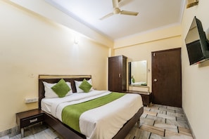 A hotel room with a bed, a wardrobe, a television, and a ceiling fan. - Hotel Royal Primes (Jaipur)