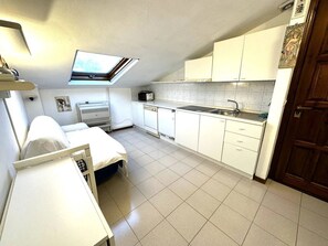 A compact kitchen with a skylight, white cabinets, a sink, and a small dining area. - New Listing (Sanremo)