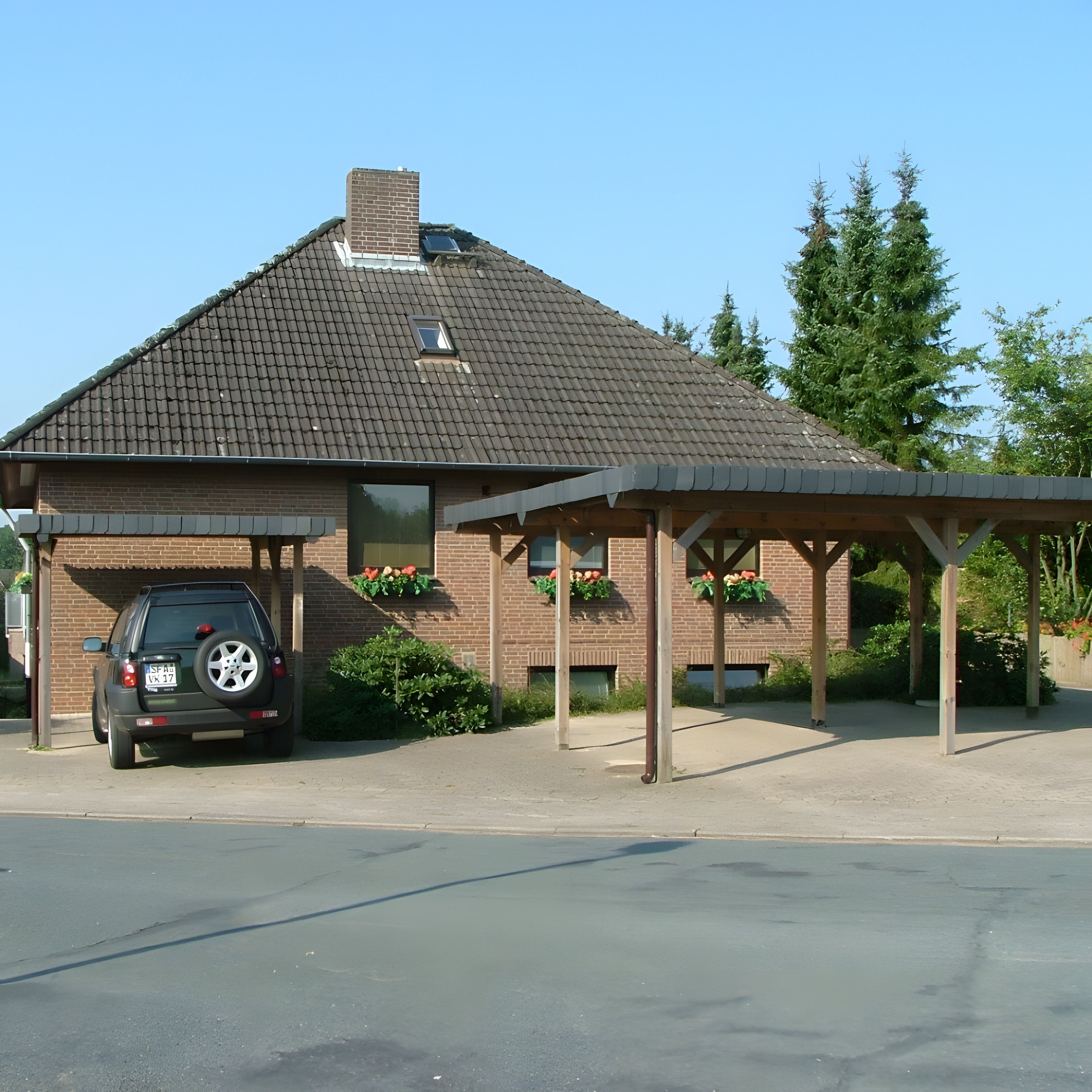 Ein Gebäude mit überdachtem Parkbereich, einer Ziegel-Fassade und einem geneigten Dach.